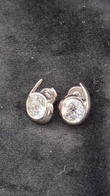 une paire de boucles d'oreilles en diamant posées sur un tissu noir