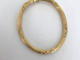 a close up of a gold bracelet on a white surface