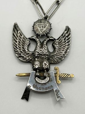 a close up of an eagle with a sword and shield on a chain