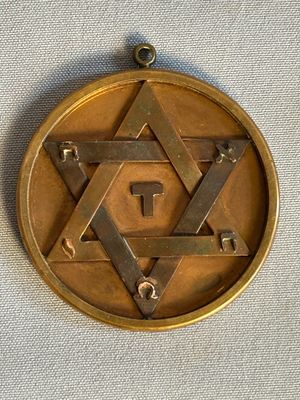 une étoile de David sur une médaille en or posée sur un tissu blanc