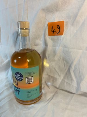 a bottle of alcohol sitting on a bed next to a pillow