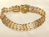 a close up of a gold bracelet with a coin on it