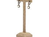 a close up of a pair of earrings on a stand on a white background
