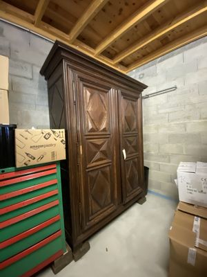 une armoire en bois au milieu d'une pièce, avec des cartons et encore des cartons par terre