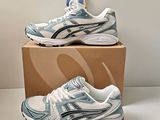 two pairs of asics running shoes are on a cardboard box