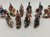 seven figurines of soldiers riding horses on a white surface