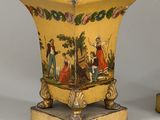 pair of yellow vases with figures painted on them sitting on a table