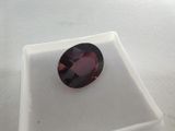 a close up of a red garnet stone sitting on a white surface
