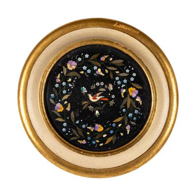 une assiette noire et dorée ornée d'un oiseau et de fleurs