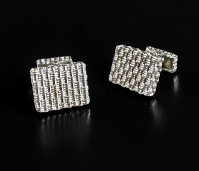 a pair of silver cufflinks on a black surface