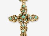 une croix en or ornée de pierres turquoise sur fond blanc