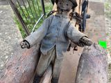 a statue of a man sitting on top of a wooden bench