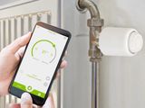 a person holding a smart phone in front of a radiator