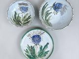 three small bowls with thistle designs on them sitting on a table