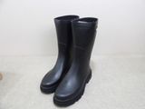 pair of black rain boots sitting on the floor next to a chair