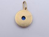 an image of a gold charm with a blue stone in the center