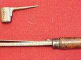 a metal tool with a wooden handle on a red surface