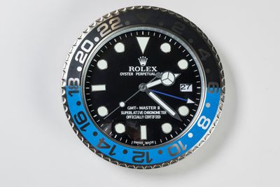 a black and blue rolex watch on a white surface