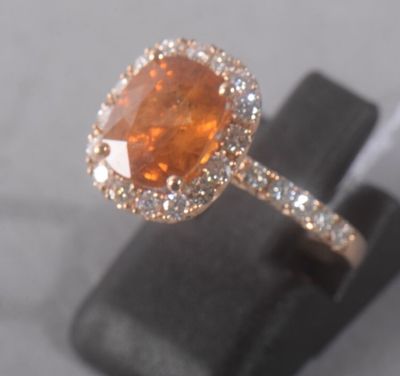 une image représentant une bague ornée d'une grosse pierre orange entourée de diamants