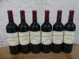 six bouteilles de vin rouge sont alignées sur une table en bois
