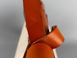 the back of a brown leather bag with a strap on it