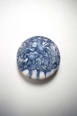 une pierre bleue et blanche sur laquelle est représenté un arbre, posée sur une surface blanche