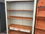 a tall white bookcase with two drawers and a shelf