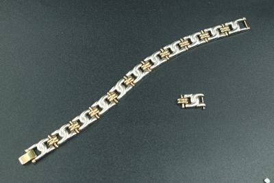 un bracelet en argent et en or et une montre posés sur une table