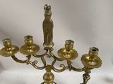 an antique brass candelab with five candles and a cat figurine