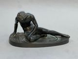 bronze statue of a woman sitting on a plate with her hands on her knees