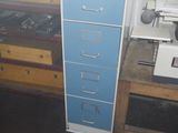 a blue filing cabinet in the corner of a room next to a window