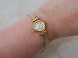 a woman ' s wrist that has a gold watch on it