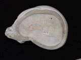 underside view of a white porcelain figurine on a black surface