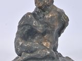statue of a man sitting on a rock with a bird in his hand