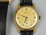 a gold wrist watch with a black leather band