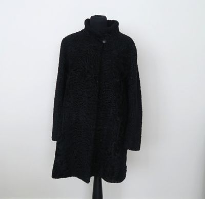 un manteau noir posé sur un mannequin, devant un mur blanc