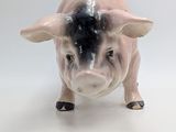 a small ceramic pig that is standing on a white surface
