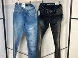 deux paires de jeans suspendues à un portant dans un magasin de vêtements