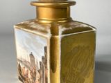 a gold bottle with a picture of a city on it