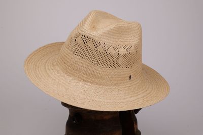 une image représentant un chapeau de paille posé sur un support en bois, sur fond blanc