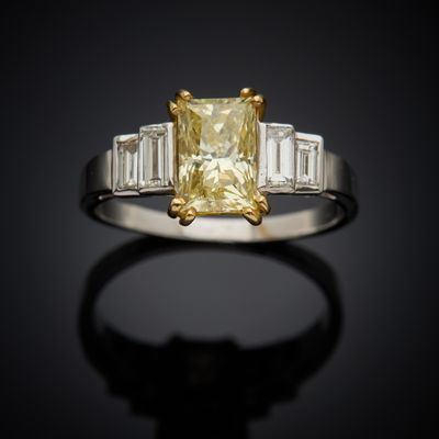a close up of a yellow diamond ring with baguets on a black background