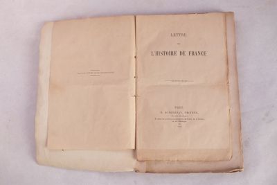 un livre ouvert posé sur une table blanche recouverte de papiers