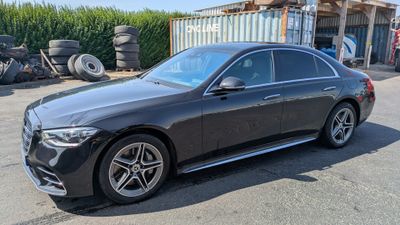 La Mercedes Classe S berline est garée devant un tas de pneus