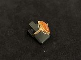 an image of a ring with an orange stone on a black surface