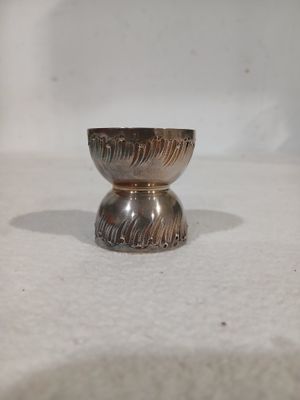 un petit bol en argent posé sur une surface blanche