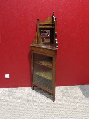 a small wooden cabinet with a glass door in the corner