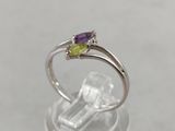 un gros plan d'une bague en argent sertie d'une pierre violette et verte