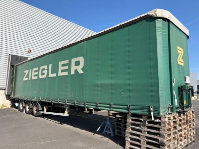 une grande remorque verte garée devant un immeuble