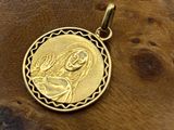 a gold pendant with a picture of the virgin mary and child