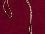 un collier en or avec une chaîne posé sur un fond de velours rouge
